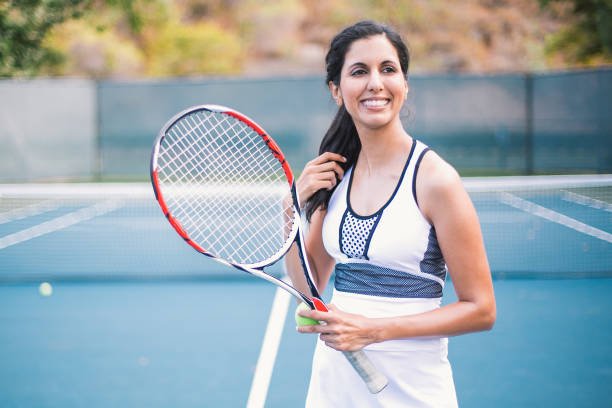 Beautiful woman of Indian ethnicity, practicing playing tennis.